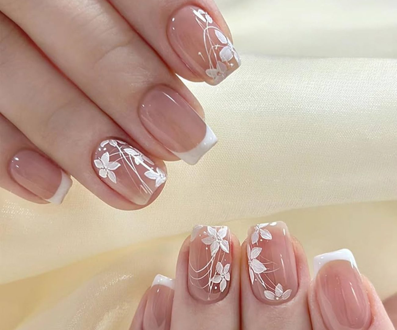 French-tip press-on nails with hand-painted white florals