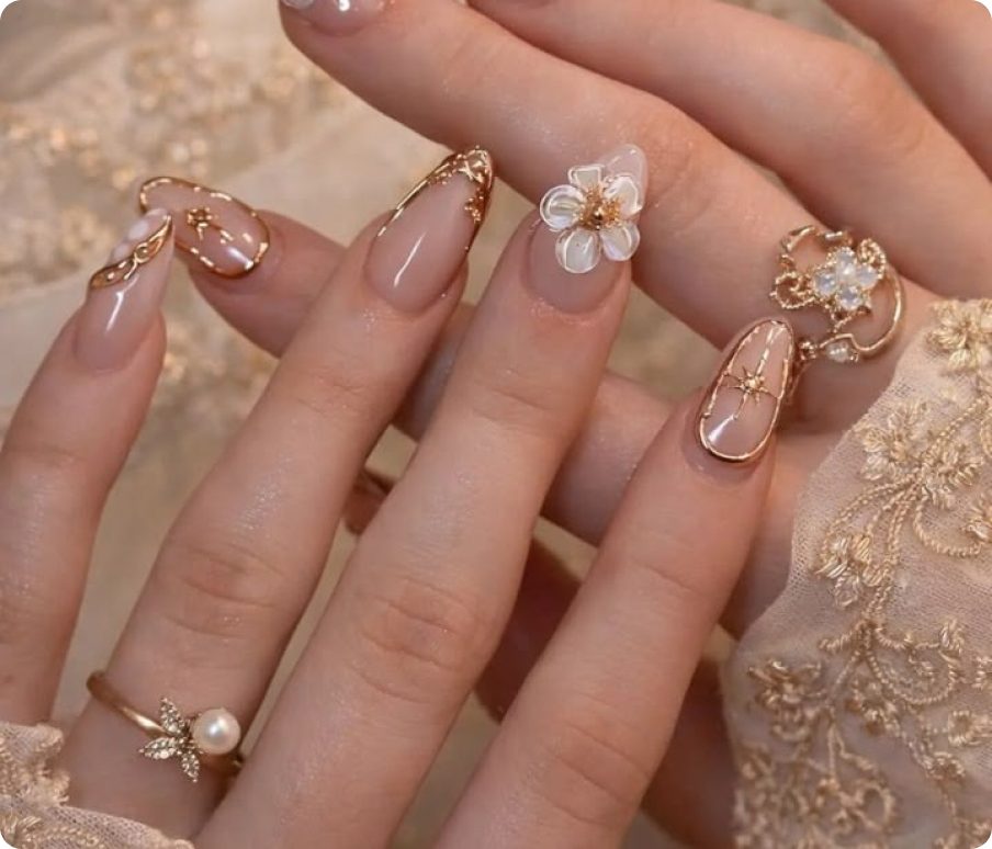 Almond press-on nails with gold accents and a white flower detail